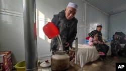 A resident boils water inside a movable plank house set up for earthquake survivors in Meipo Village, in northwest China's Gansu province, on Dec. 21, 2023. (Xinhua News Agency via AP)
