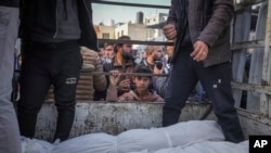 Seorang anak laki-laki melihat jenazah warga Palestina yang tewas akibat pemboman Israel di Jalur Gaza saat mereka dibawa untuk dimakamkan di Rumah Sakit Al-Aqsa di Deir al-Balah, 15 Januari 2025.
