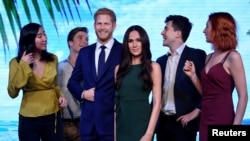 Para model berpose dengan patung lilin Pangeran Harry dan tunangannya Meghan Markle yang dipamerkan di Museum Madame Tussauds di London, Inggris, 9 Mei 2018.