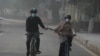 Warga tampak mengenakan masker saat bersepeda di jalanan Kota Lahore, Pakistan, pada 3 November 2024. (Foto: AP/K. M. Chaudary)