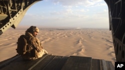 FILE - An Emirati gunner watches for enemy fire from the rear gate of a United Arab Emirates Chinook military helicopter flying over Yemen. Qatar and the Arab nations now allied against it have made inroads in the Horn of Africa in recent years by establishing military bases now being used in the Yemen war, as well as managing ports and showering friendly nations with foreign aid.