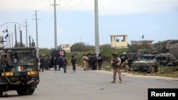 Italian and Somali security forces are seen near armored vehicles at the scene of an attack on a Italian military convoy in Mogadishu, Somalia, Sept. 30, 2019.