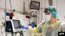 The director of the epidemics service Dr Karina Glick checking a medical ventilator control panel at a ward, while wearing protective clothing. 