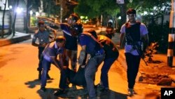 一组枪手袭击了孟加拉国首都达卡一家很受外国人欢迎的餐厅后，人们在帮助一名身份不明的受伤者。