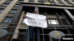 FILE - A lone activist protests against a law targeting foreign-funded NGOs in Russia, outside the Duma, Russia's lower house of parliament, in Moscow. His placard reads "Tightening laws concerning NGOs [attests to the] the paranoia of authorities."