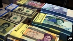 Uang kertas Iran dan AS terlihat di toko penukaran mata uang di pusat kota Teheran, Iran. (Foto: AP)