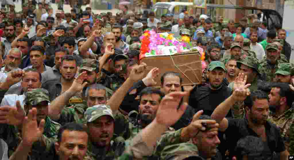 Mourners chant slogans against the Islamic State group as they carry the flag-draped coffins of three members of the Peace Brigades, a Shi'ite militia group loyal to Shi'ite cleric Muqtada al-Sadr during their funeral processions in Najaf, May 27, 2015.