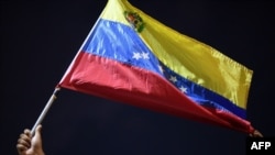 Un hombre muestra una bandera venezolana durante protesta en Güiria, en el venezolano estado Sucre, tras naufragio de una embarcación con venezolanos. Diciembre 18, 2020. [AFP]