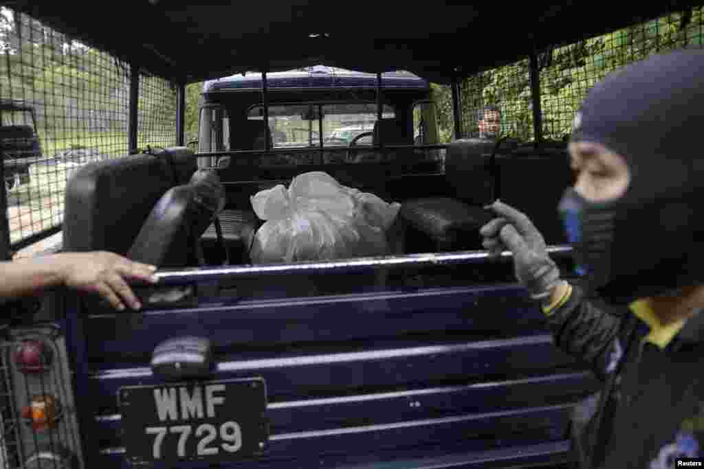 Tim forensik polisi mengangkut kantung jenazah berisi sisa-sisa mayat manusia yang digali dari kuburan dekat kamp perdagangan manusia yang ditelantarkan di hutan dekat perbatasan Thailand di Bukit Wang Burma, Malaysia utara (27/5). (Reuters/Damir Sagolj)