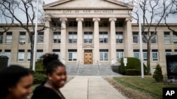 Para pejalan kaki melewati Balai Kota New Rochelle, 10 Maret 2020, di New York. Pejabat negara bagian menutup beberapa sekolah dan rumah ibadah di New York untuk penanganan wabah virus corona.