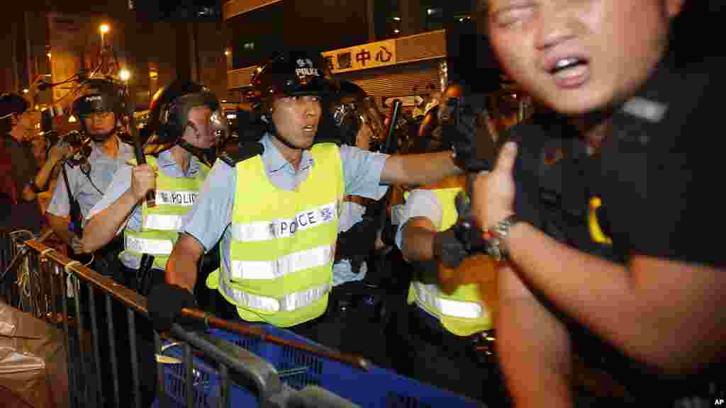 A pro-democracy protester is struck by a baton as riot police move on an occupied section of a roadway in the Mong Kok district of Hong Kong, Oct. 18, 2014.