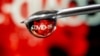 FILE - "COVID-19" is reflected in a drop on a syringe needle in this illustration taken Nov. 9, 2020. 
