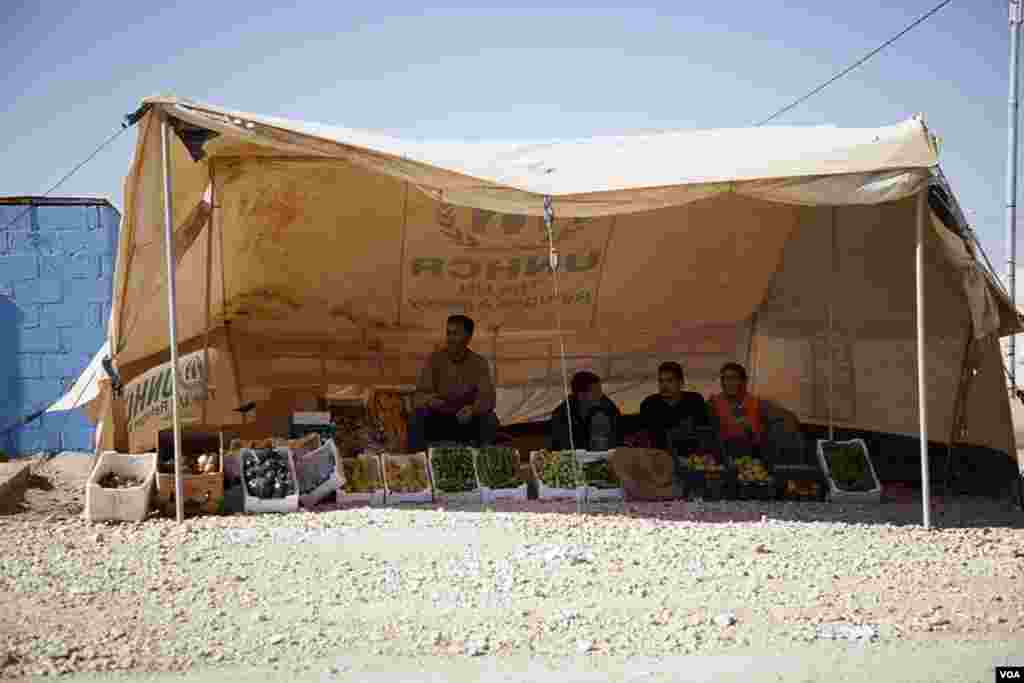 A vegetable vendor has set up shop along the main road that runs through the Za'tari refugee camp. Other makeshift shops sell shoes, clothing and prepared foods. (Y. Weeks/VOA)