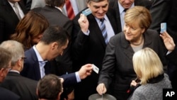 German Chancellor Angela Merkel, right, casts her vote at the German Federal Parliament in Berlin, Germany, Dec.4, 2015. 