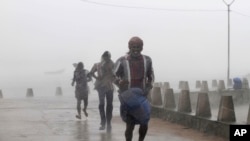 People run for shelter as heavy rain and wind gusts rip through the Bay of Bengal coast at Gopalpur, Orissa, about 285 kilometers (178 miles) north east of Visakhapatnam, India, Sunday, Oct. 12, 2014. 