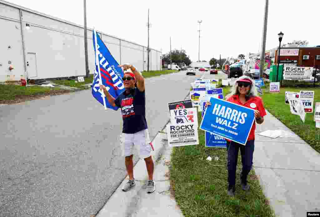 Robert Browning (L) and Terri Bieberbach wave campaign sings outside of a polling precinct on Election Day at the Town 'N Country Regional Public Library in Tampa, Florida.