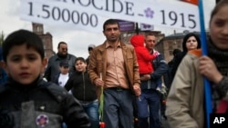 FILE - Armenians carry a placard with a sign reading "1915" and "1500000", the year and numbers of victims of mass killings of Armenians by Ottoman Turks on a city street in Yerevan, Armenia, April 24, 2015. 