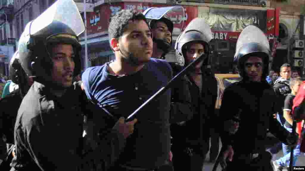 Riot police detain a man who was taking part in a protest against a new law in Egypt that restricts demonstrations, in downtown Cairo, Nov. 26, 2013.