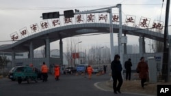 资料照：中国新疆和田居民走过“和田市纺织服装实训就业基地”的工厂大门。（2019年10月1日）