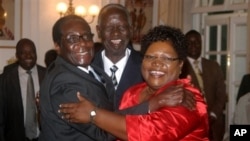 FILE: Zimbabwean President Robert Mugabe, left, celebrates with newly sworn-in vice presidents Joyce Mujuru, right, and Joseph Msika, center, State House, Harare, Oct. 2008 file photo.