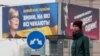 A woman stands in front of pre-election posters of opposition politician Yulia Tymoshenko and Ukrainian President Petro Poroshenko in Kyiv, Ukraine, Feb. 20, 2019. 