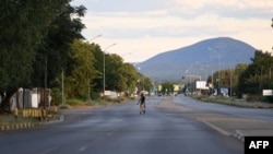 A pedestrian walks across an empty road, which usually experiences heavy traffic, in Gaborone on April 5, 2020, the third day of the state of emergency in Botswana.