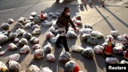 中国陕西西安新冠防疫封城后一名工作人员为居家隔离的小区居民准备递送食品。（2021年12月23日）