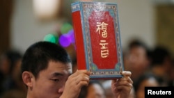 資料照：北京一家天主教堂在做聖誕彌撒時一名神職人員手舉聖經。 （2014年12月24日）
