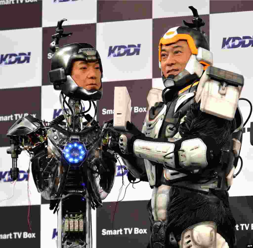 Japanese actor Ken Matsudaira (R), clad in a robot suit, takes part in a press presentation with an android robot (L) in his likeness called "Real Android Matsuken" in Tokyo. The android robot was developed for an advertisement for Japanese telecom company KDDI.