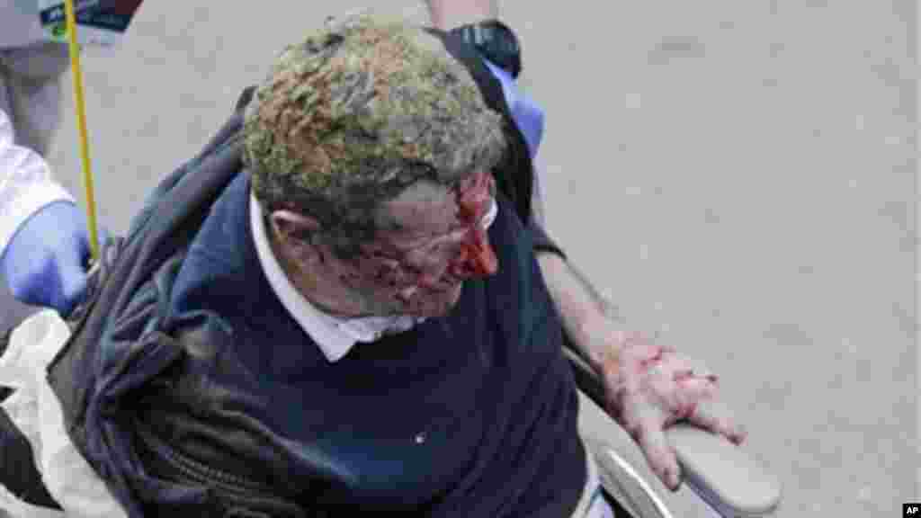 Paramédicos ajudam um homem ferido junto à linha de chegada da Maratona de Boston após a dupla explosão de segunda-feira (15 de Abril de 2013).