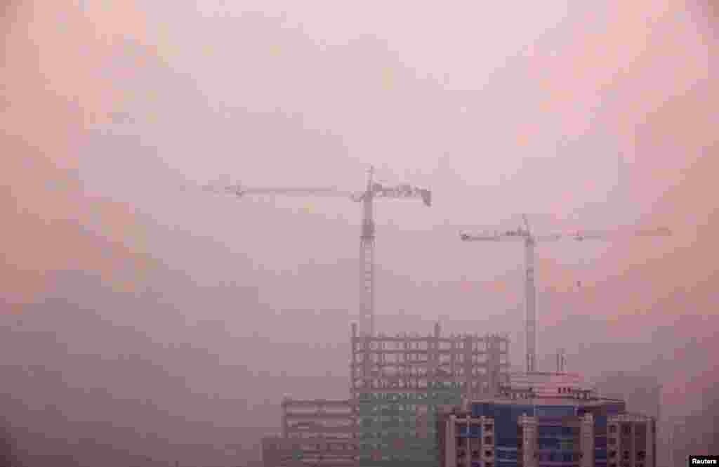 Cranes atop a residential building under construction in central Beijing, April 18, 2012.