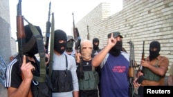FILE - Masked Sunni gunmen pose during a patrol outside Fallujah, Iraq, April 28, 2014. 