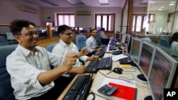 Indian stockbrokers celebrate as they watch the Bombay Stock Exchange (BSE) index on their trading terminal in Mumbai, India.