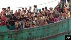FILE - Migrants sit on their boat as they wait to be rescued by Acehnese fishermen on the sea off East Aceh, Indonesia, Wednesday, May 20, 2015. Hundreds of migrants stranded at sea for months were rescued and taken to Indonesia, officials said. 