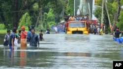 A truck carries people past a flooded road in Thrissur, in the southern Indian state of Kerala, Aug. 18, 2018. Rescuers used helicopters and boats Friday to evacuate thousands of people stranded on their rooftops following unprecedented flooding in the so