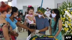 TOPSHOT - Indigenous from the Parque das Tribos community mourn besides the coffin of Chief Messias, 53, of the Kokama tribe who died victim of the new coronavirus, COVID-19, in Manaus, Brazil, on May 14, 2020. (Photo by MICHAEL DANTAS / AFP)