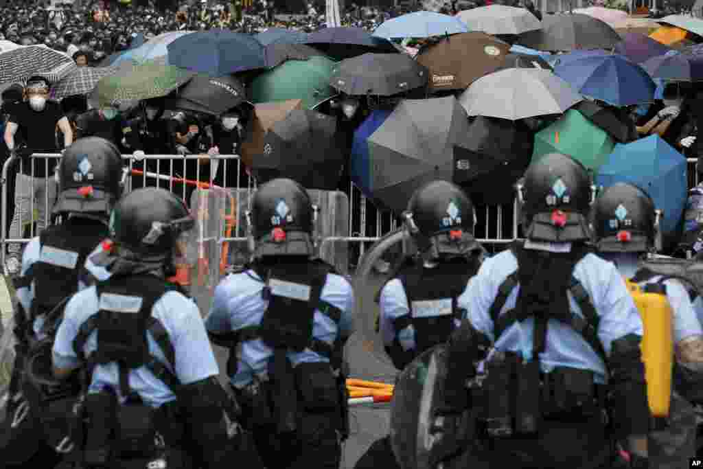 2019年6月12日在香港立法會附近,帶有防暴裝備的警察與打著雨傘的示威者對峙。