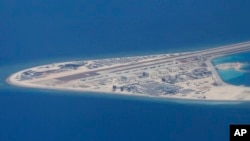 菲律宾空军一架运输机在南中国海南沙群岛的中国制造的人造岛礁渚碧礁上空飞越时拍摄的照片，显示人造岛礁上的简易机场和建筑物。（2017年4月21日）