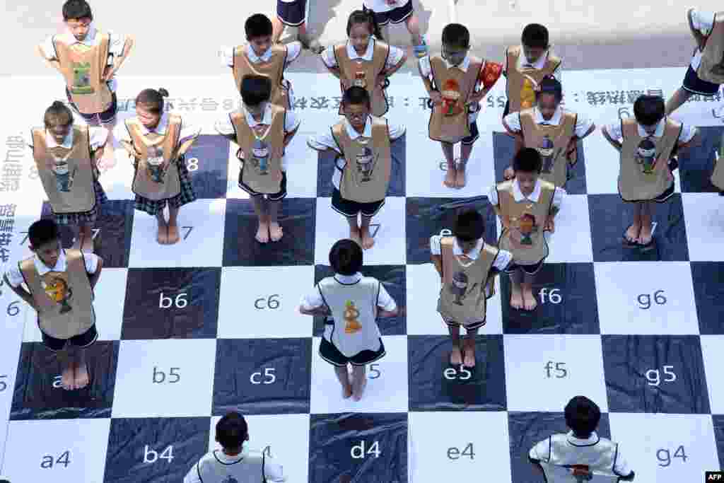 Anak-anak bermain catur di papan catur raksasa di sekolah dasar di Handan di provinsi Hebei yang terletak di bagian utara China. Pertandingan catur “langsung” dimainkan oleh 32 siswa untuk mempromosikan permainan catur di sekolah.