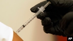 FILE - A woman is injected with her second dose of the Pfizer COVID-19 vaccine at a Dallas County Health and Human Services vaccination site in Dallas, Aug. 26, 2021. 