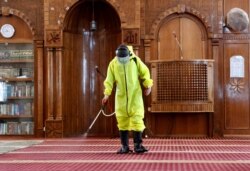A Gaza municipality worker wearing protective gear sprays disinfectant as a precaution against the coronavirus, inside Beach Mosque in Gaza City, May 21, 2020.