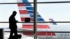 FILE - A passenger talks on the phone as American Airlines jets sit parked at their gates at Washington's Ronald Reagan National Airport, Jan. 25, 2016. A civil rights group is suing the Trump administration for details on how data found by immigration officials on travelers' electronic devices is kept or shared.