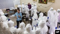 Una trabajadora de la Organización Mundial de Salud entrena enfermeras en el uso de equipo protector contra el ébola.