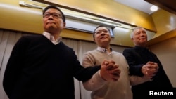 Benny Tai You-ting (tengah), Chan Kin-man (kiri), dan pendeta Chu Yiu-ming bergandengan tangan saat menggelar konferensi pers di Hong Kong (2/12).
