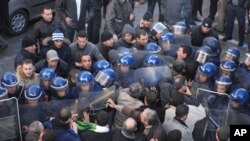 Demonstrators, foreground, asking for political change in their country, face riot policemen, in Algiers, Algeria, 22 Jan 2011