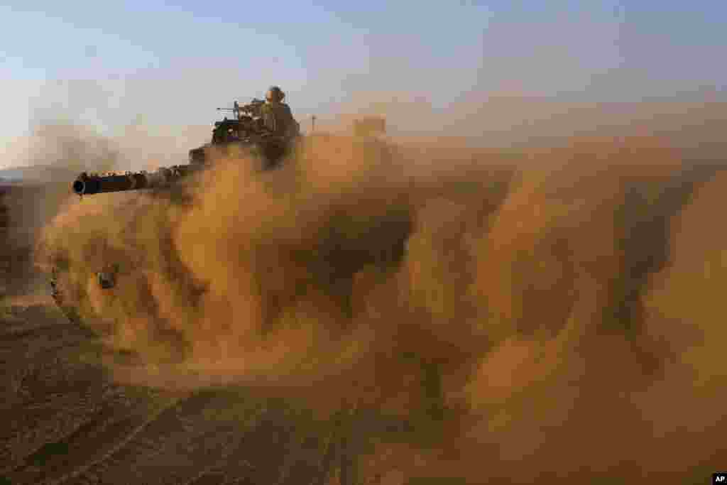 Israeli soldiers drive a tank at a staging area in the Golan Heights, near the border between the Israeli-controlled Golan Heights and Syria.