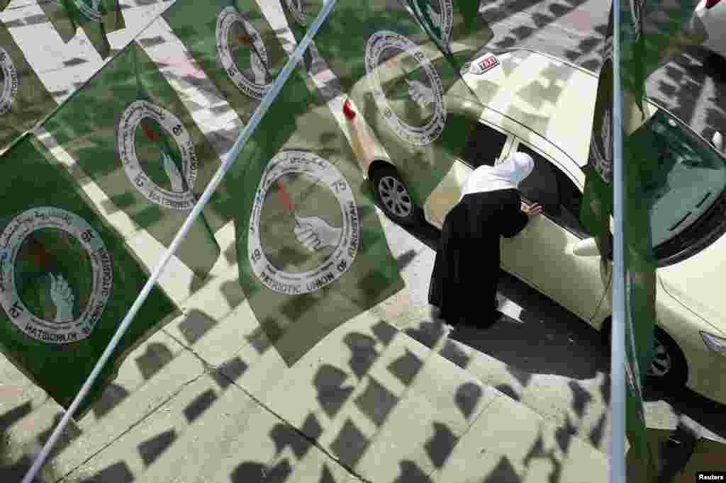 A woman hails a taxi while standing under Patriotic Union of Kurdistan (PUK) campaign flags before Iraq's parliamentary elections, Sulaimaniya, April 28, 2014.