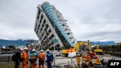Tim SAR dari Jepang (kiri) dan Taiwan (kanan) mengamati bangunan Yun Tsuiyang di kota Hualien, Taiwan yang terlihat miring dan membahayakan, Jumat (9/2). Taiwan mulai menghancurkan tiga bangunan yang dianggap berbahaya setelah kawasan tersebut diguncang gempa berkekuatan 6.4 SR, 6 Februari 2018.