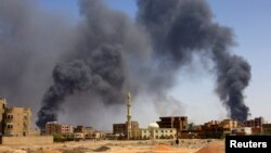 FILE - A man walks while smoke rises above buildings after aerial bombardment, during clashes between the paramilitary Rapid Support Forces and the army in Khartoum North, Sudan, May 1, 2023. 