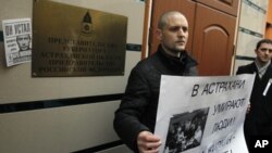 Russian opposition leader Sergei Udaltsov holds a placard during a rally outside the representative offices of the Astrakhan region during a rally in Moscow, April 9, 2012.